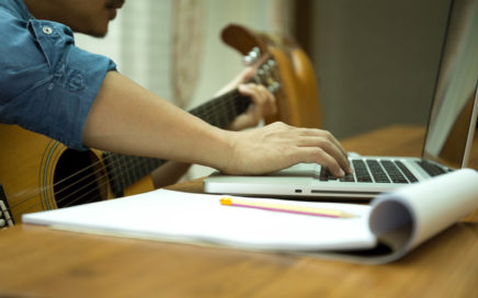 Songwriter with guitar and paper