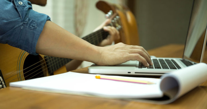 Songwriter with guitar and paper